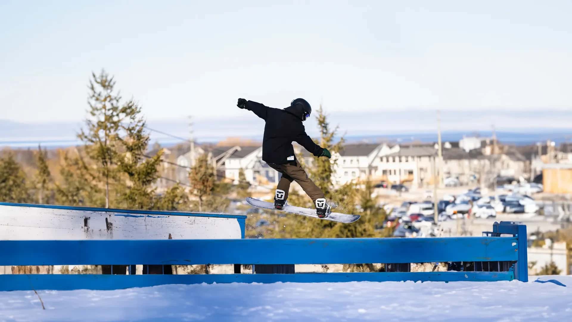 Snowboarder jibbing along a long box in the Blue Mountain Resort terrain park during spring skiing.