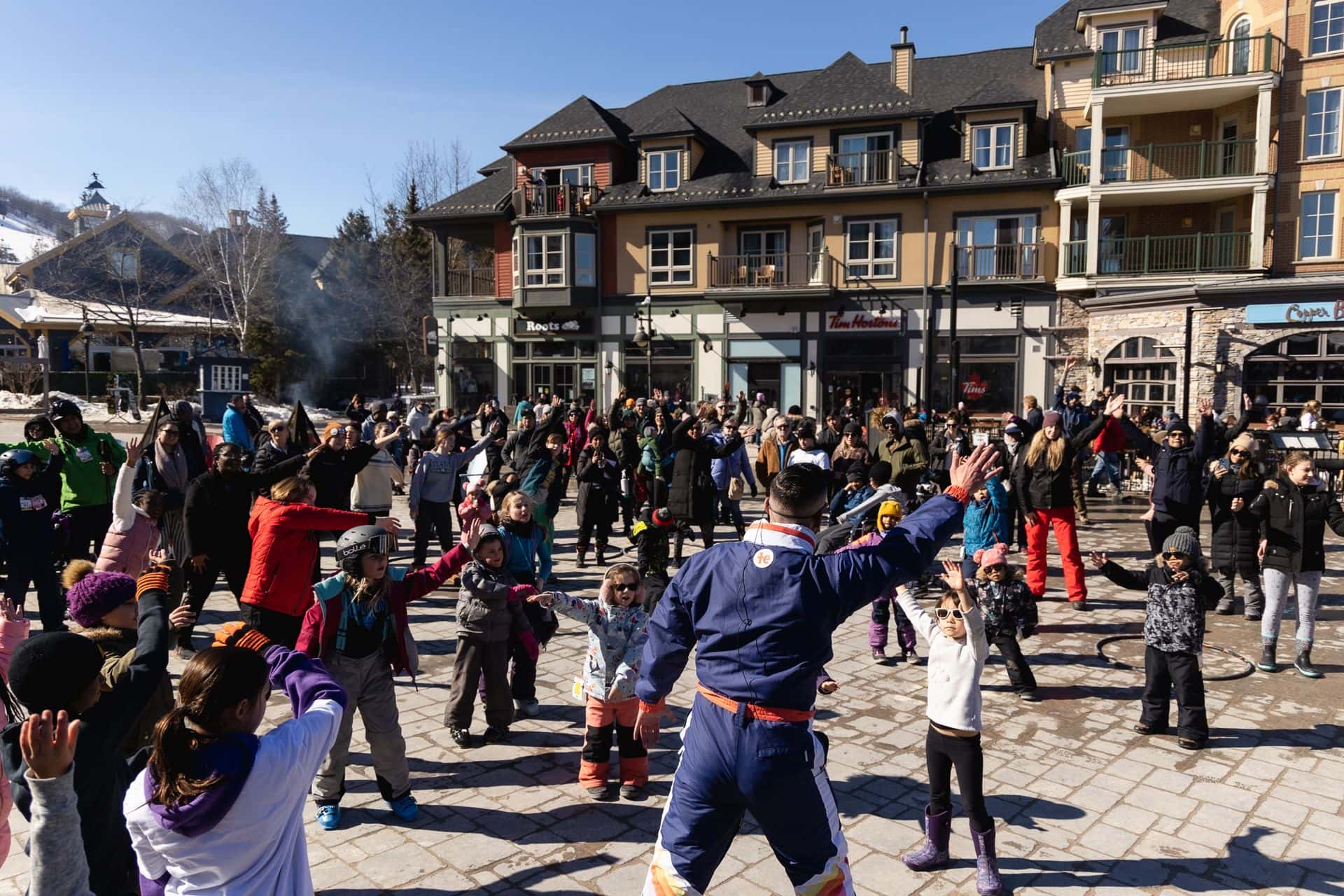 A crowd of guest fill the events plaza, following along to Groove Dancing with Tyler Boyle in the Village.