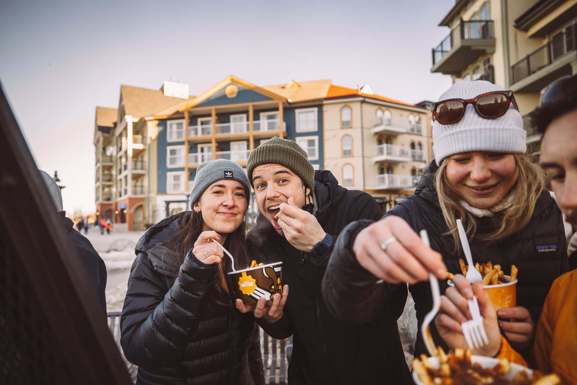 A group of friends enjoy Mile High Poutine outisde in the village.