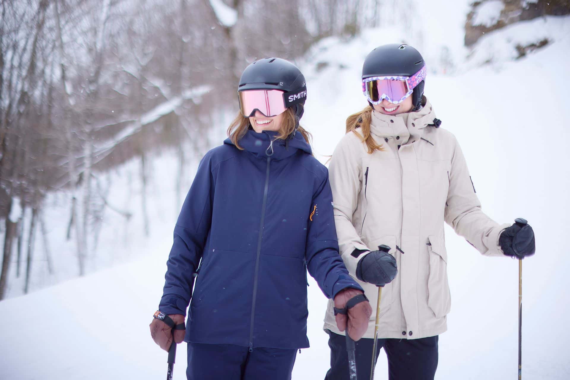 Two female skiers staring down the mountain in full ski gear. 