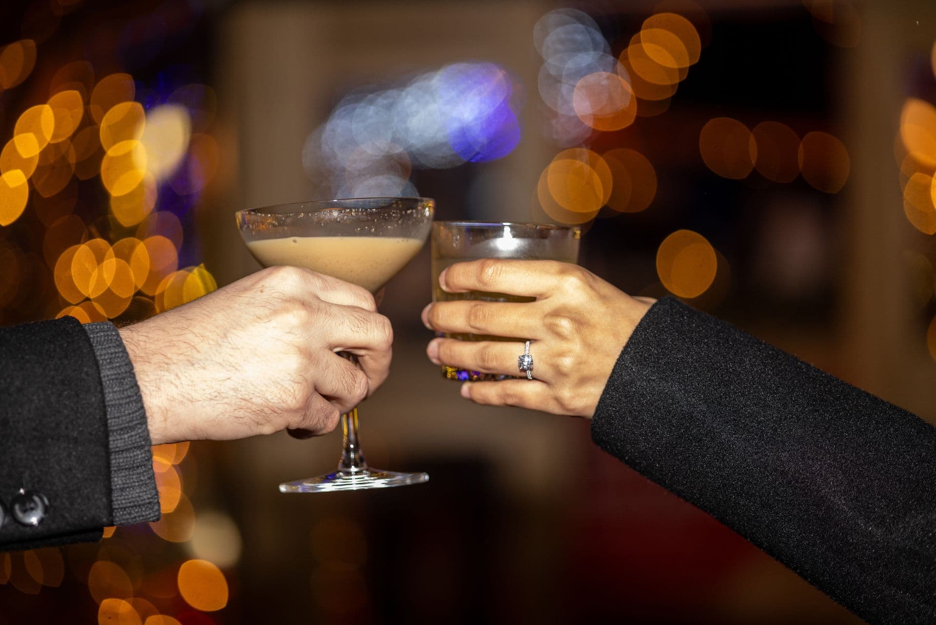 Closeup shot of couple cheersing together festive drinkss in the Snowdome Cocktail Garden.