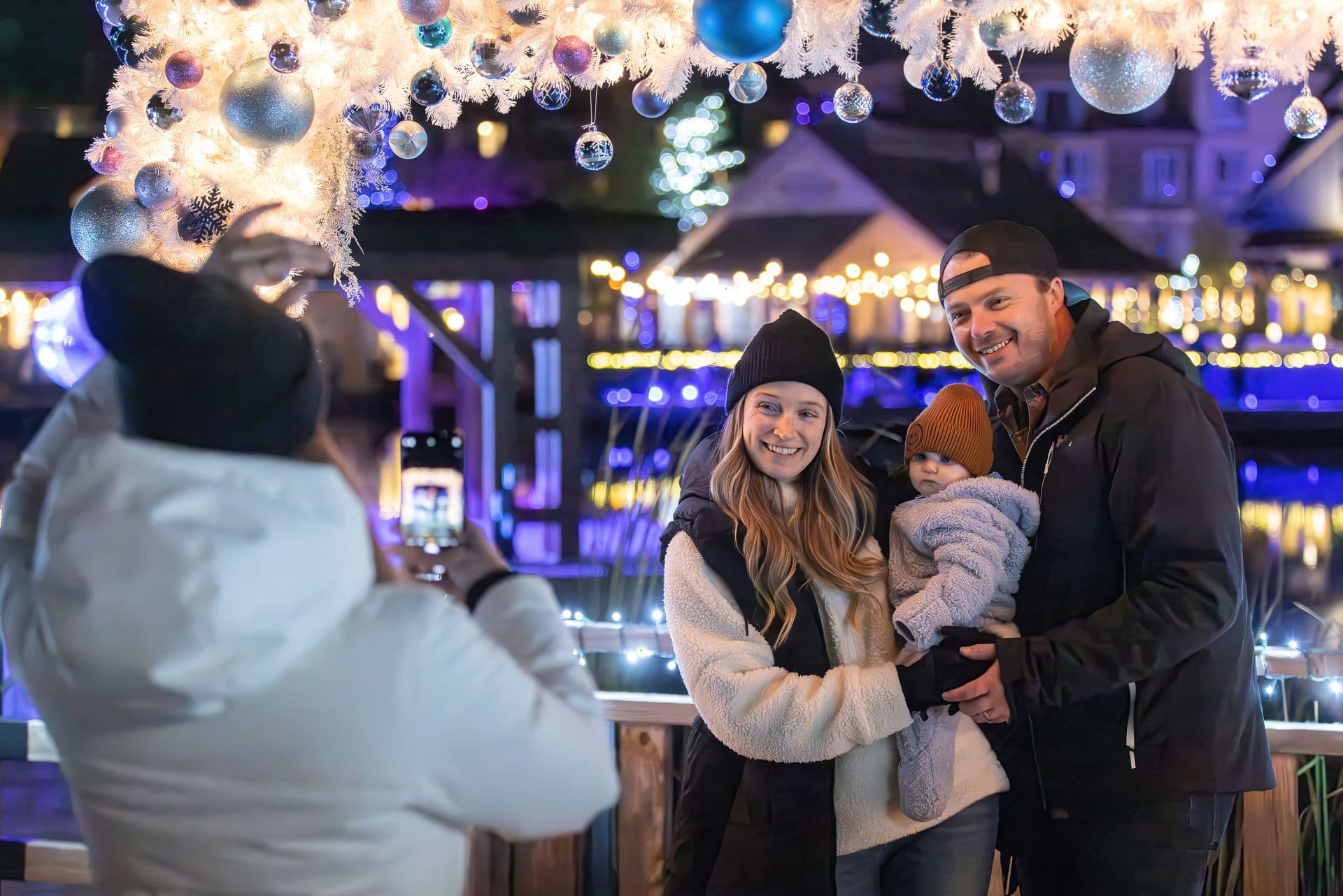 Family of three having their photo taken in the festively adorned photo frame along the Holiday Magic Light Trail