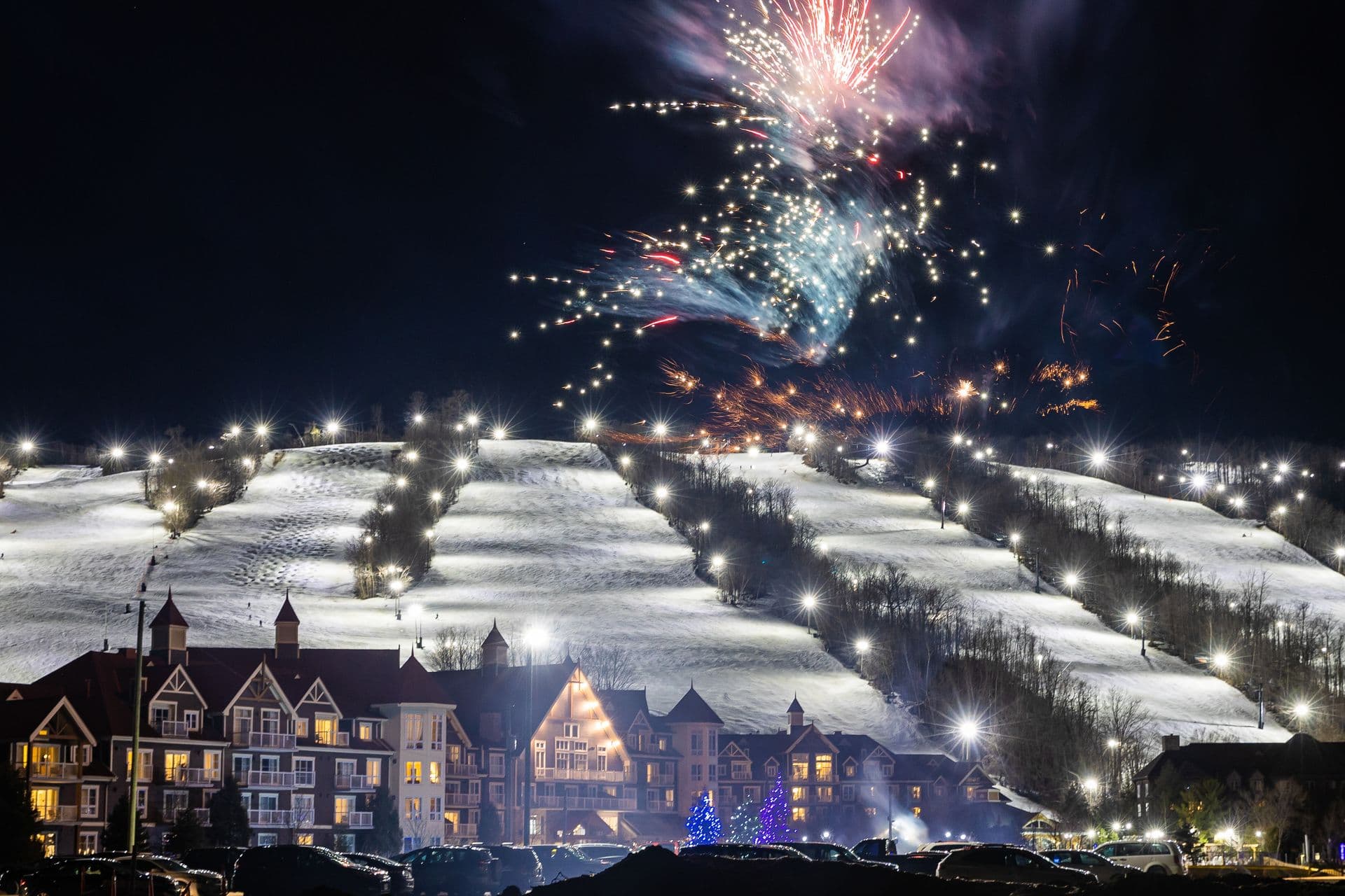 Fireworks bursting over the lit up Village and snow covered Mountain for New Years Eve at Blue.