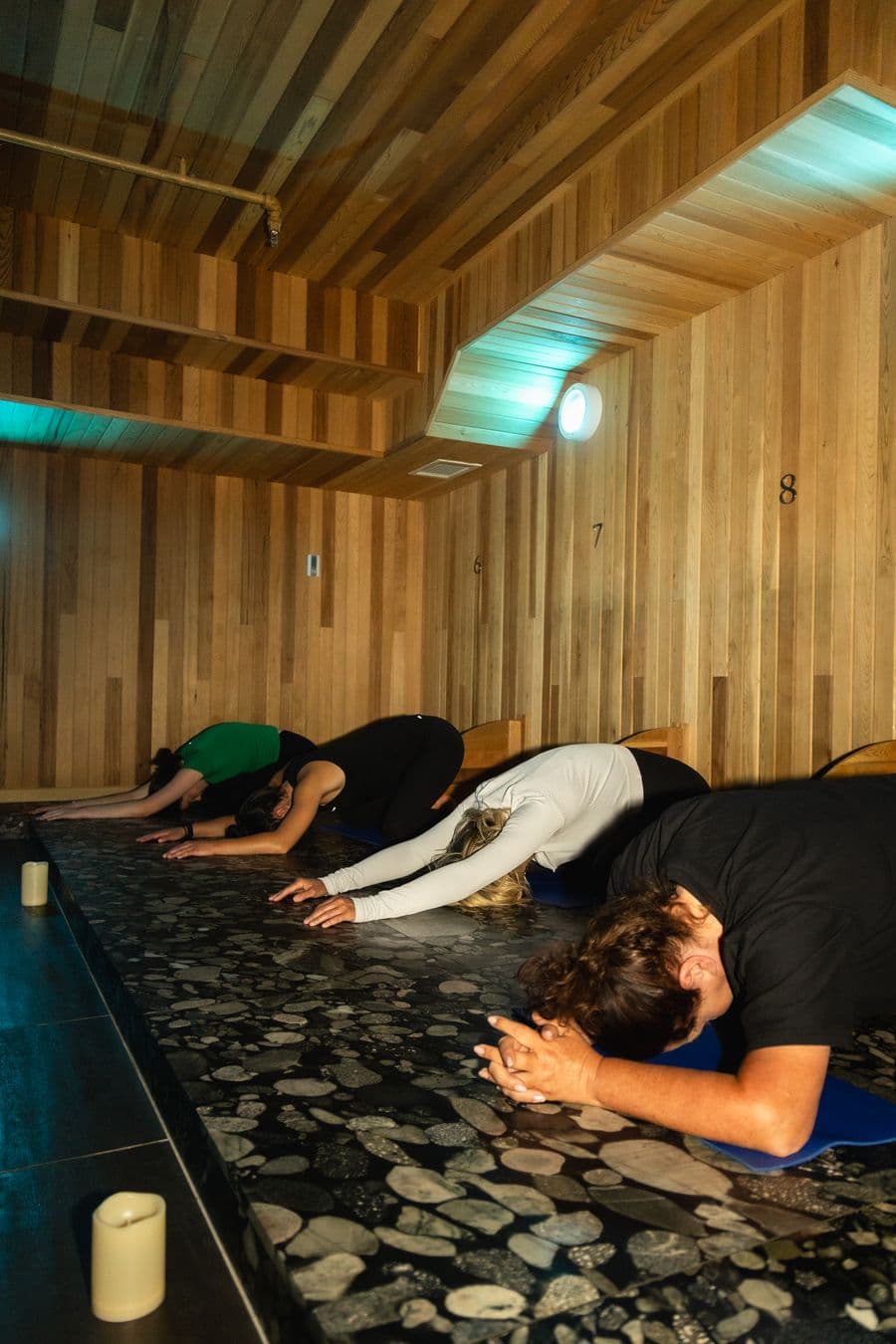 Group of women in balasana yoga pose in iwa Spa's heated Volcanic rock room.