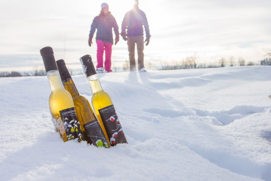 A couple snowshoeing on the Apple Pie Trail, with wine bottles in the foreground. 