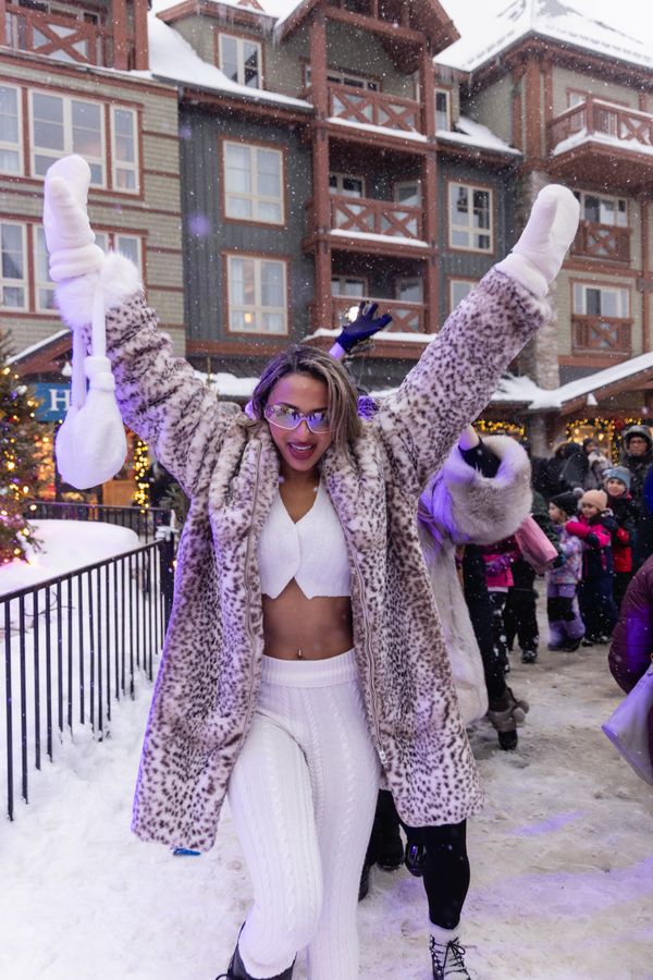 Woman dressed in a fur coat, hands in the air, dancing to the Caribbean Winterfest music.