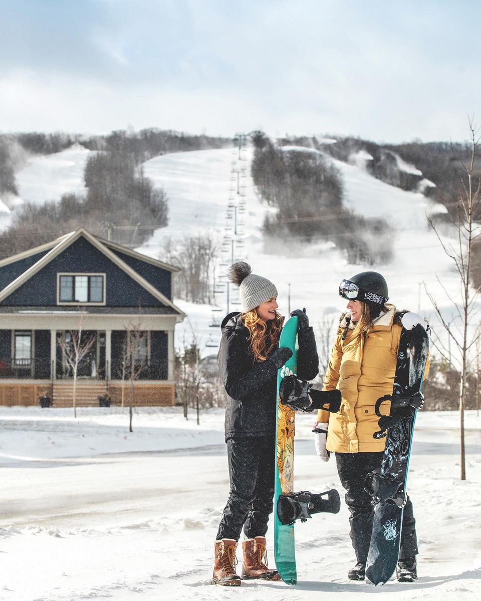 Two snowboarders getting ready to take on the mountain from their private home accommodations at Windfall.