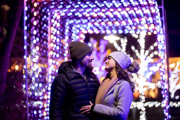 Couple embracing each other beneath the glowing lights of the Holiday Magic Light Trail at Blue Mountain Village