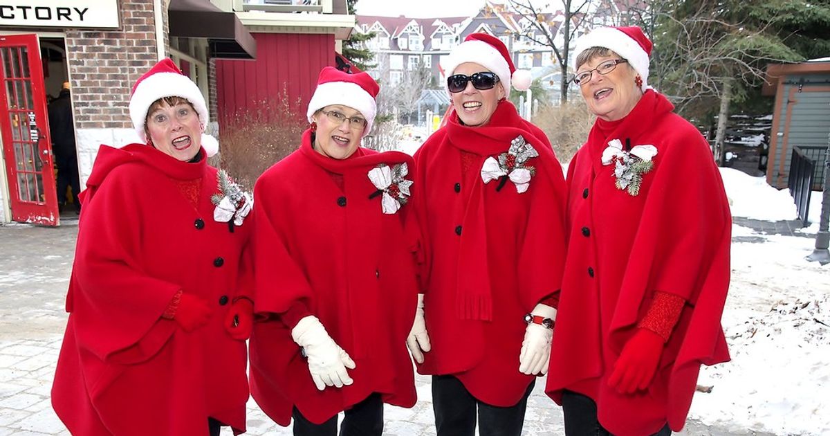 Rhythmix Quartet, (Doris, Sue, Jan, & Marion), dressed in red coats and Santa hats, singing Christmas carols acapella in the Village Plaza