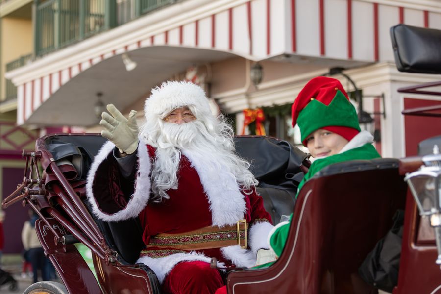 Santa and his holiday elf wave to the camera as the pass through the Village on Horse & Carriage.