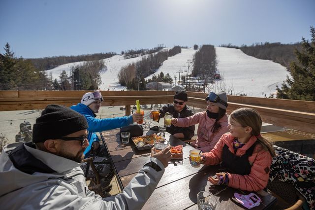 Family cheers their drinks together after a day of skiing on the Rusty's outdoor patio.