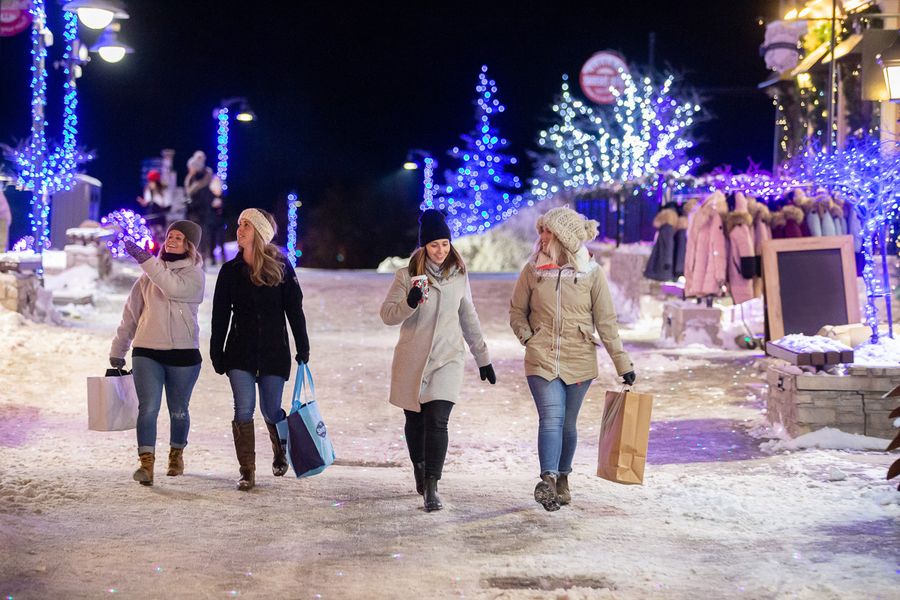 Group of four friends shop the Village as they stroll through the festively lit Holiday Magic Light Trail.