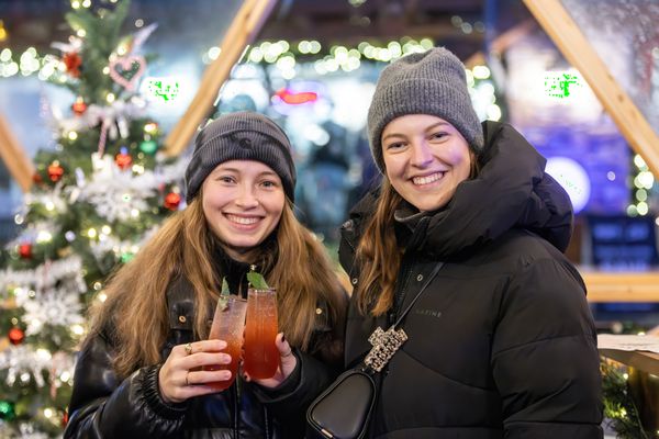 Two girls smiling to the camera, holding festive cocktails in the Snowdome Cocktail Garden.