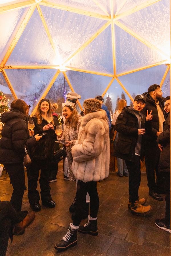 Large friend group of young adults wearing fur coats and traditional Après wear inside the Snowdome Cocktail Bar